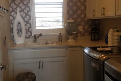 Example of a large eclectic galley medium tone wood floor and wallpaper utility room design in Denver with a drop-in sink, white backsplash, mosaic tile backsplash, beige walls and a side-by-side washer/dryer