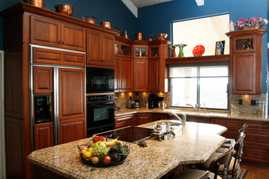 Eat-in kitchen - mid-sized traditional l-shaped medium tone wood floor eat-in kitchen idea in Sacramento with a double-bowl sink, raised-panel cabinets, medium tone wood cabinets, granite countertops, stone slab backsplash, black appliances and an island