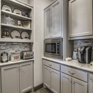 Large transitional kitchen pantry ideas - Inspiration for a large transitional dark wood floor and brown floor kitchen pantry remodel in Dallas with a farmhouse sink, recessed-panel cabinets, gray cabinets, granite countertops, gray backsplash, glass tile backsplash, stainless steel appliances and two islands