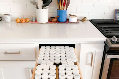 Mid-sized minimalist l-shaped medium tone wood floor and brown floor eat-in kitchen photo in Raleigh with a farmhouse sink, recessed-panel cabinets, white cabinets, quartz countertops, white backsplash, subway tile backsplash, stainless steel appliances, an island and white countertops