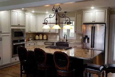 Inspiration for a mid-sized transitional l-shaped medium tone wood floor and brown floor eat-in kitchen remodel in Other with recessed-panel cabinets, stainless steel appliances, a farmhouse sink, white cabinets, granite countertops, beige backsplash, travertine backsplash, an island and brown countertops