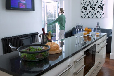 Inspiration for a large modern kitchen/diner in Manchester with white cabinets, granite worktops, multiple islands and black worktops.