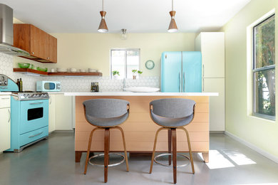 Kitchen - mid-sized mid-century modern l-shaped concrete floor and gray floor kitchen idea in Austin with a farmhouse sink, flat-panel cabinets, medium tone wood cabinets, quartz countertops, ceramic backsplash, colored appliances, an island and white countertops