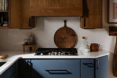 Small trendy l-shaped light wood floor eat-in kitchen photo in Detroit with an undermount sink, flat-panel cabinets, blue cabinets, quartz countertops, white backsplash, quartz backsplash, paneled appliances, no island and white countertops