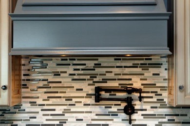 Example of a mid-sized eclectic kitchen design in Louisville with raised-panel cabinets, granite countertops, multicolored backsplash, matchstick tile backsplash and paneled appliances