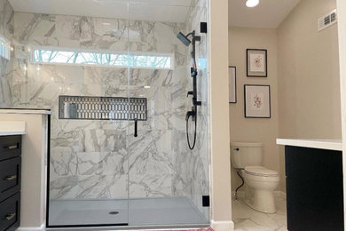 Design ideas for a mid-sized transitional master bathroom in St Louis with shaker cabinets, black cabinets, gray tile, porcelain tile, porcelain floors, engineered quartz benchtops, a hinged shower door, white benchtops, a niche, a single vanity, a built-in vanity, vaulted and wallpaper.