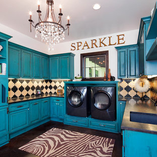 Ejemplo de cuarto de lavado en U, clásico, grande, con fregadero bajoencimera, armarios con paneles con relieve, puertas de armario azules, paredes blancas, lavadora y secadora juntas, suelo marrón y encimeras negras