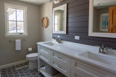 Photo of a mid-sized 3/4 bathroom in Minneapolis with flat-panel cabinets, white cabinets, an alcove shower, a two-piece toilet, white tile, subway tile, grey walls, porcelain floors, an undermount sink, engineered quartz benchtops, multi-coloured floor, a hinged shower door and white benchtops.