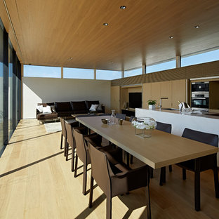 Exempel på en modern matplats med öppen planlösning, med vita väggar, beiget golv och plywoodgolv