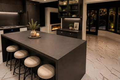 Large galley marble floor, white floor and coffered ceiling eat-in kitchen photo in Toronto with flat-panel cabinets, black cabinets, quartzite countertops, an island, an undermount sink, beige backsplash, stone slab backsplash, black appliances and black countertops