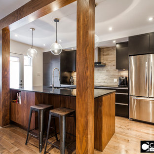 Mid-sized contemporary kitchen pantry ideas - Mid-sized trendy galley medium tone wood floor kitchen pantry photo in Montreal with an integrated sink, flat-panel cabinets, black cabinets, quartzite countertops, gray backsplash, stone tile backsplash, stainless steel appliances and an island