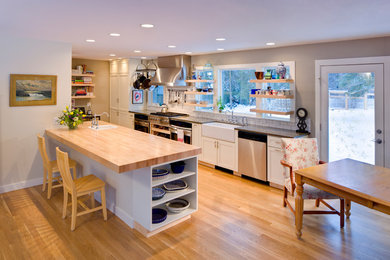 Example of a transitional galley light wood floor eat-in kitchen design in Other with a farmhouse sink, shaker cabinets, white cabinets, white backsplash, subway tile backsplash, stainless steel appliances and a peninsula