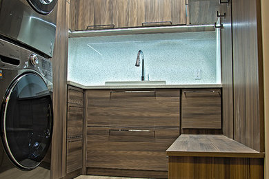 Inspiration for a mid-sized modern u-shaped porcelain tile and beige floor dedicated laundry room remodel in Miami with flat-panel cabinets, dark wood cabinets, a stacked washer/dryer and a drop-in sink