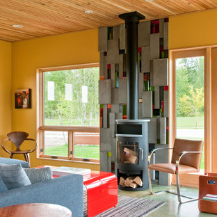 Modern inredning av ett stort allrum med öppen planlösning, med gula väggar, en öppen vedspis, ett finrum, betonggolv och en spiselkrans i metall