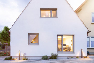 Kleines, Zweistöckiges Modernes Einfamilienhaus mit Putzfassade, weißer Fassadenfarbe, Satteldach und schwarzem Dach in Sonstige