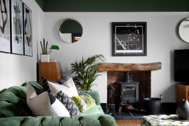 マンチェスターにあるお手頃価格の中くらいなトランジショナルスタイルのおしゃれな独立型リビング (白い壁、無垢フローリング、薪ストーブ、木材の暖炉まわり、据え置き型テレビ) の写真
