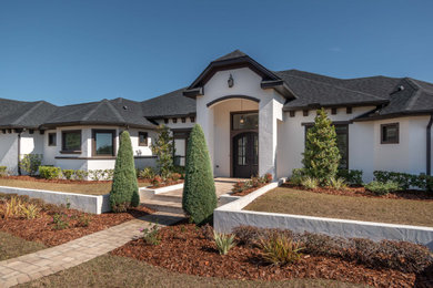 Inspiration for a large white one-story stucco house exterior remodel in Orlando with a shingle roof and a gray roof