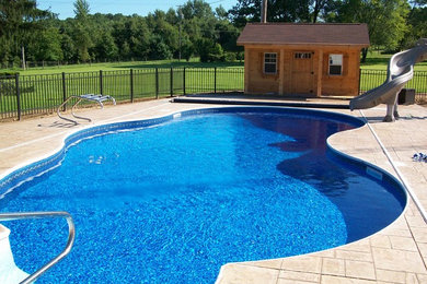 Design ideas for a mid-sized backyard custom-shaped pool in Cleveland with a pool house and stamped concrete.