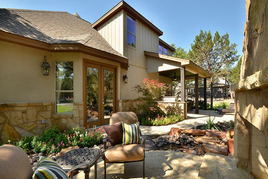 Example of a classic stone patio fountain design in Austin with a roof extension
