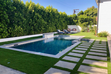 Diseño de piscina moderna de tamaño medio rectangular en patio trasero con paisajismo de piscina y adoquines de hormigón