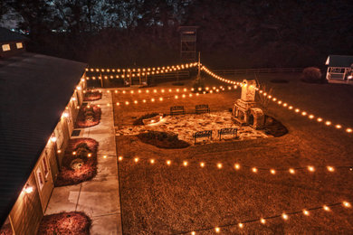Example of a large country side yard stone patio design in Atlanta with a fireplace and no cover