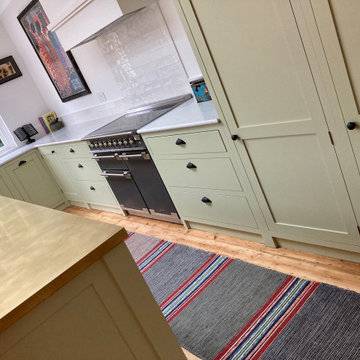 Light green cottage style kitchen with white worktops and kitchen island