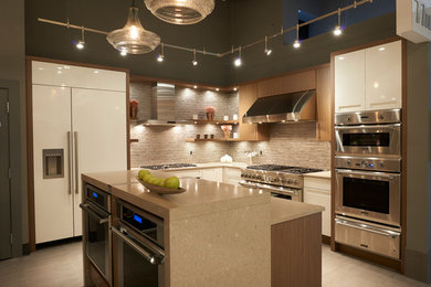 Example of a mid-sized minimalist l-shaped porcelain tile kitchen design in Vancouver with flat-panel cabinets, an island, white cabinets, limestone countertops, beige backsplash, matchstick tile backsplash and stainless steel appliances