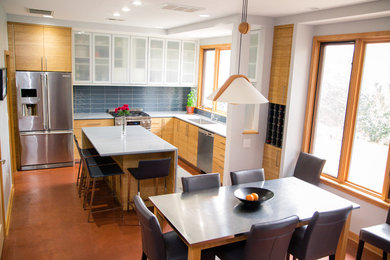 Photo of a mid-sized modern l-shaped eat-in kitchen in Raleigh with a single-bowl sink, flat-panel cabinets, light wood cabinets, recycled glass benchtops, stainless steel appliances and with island.