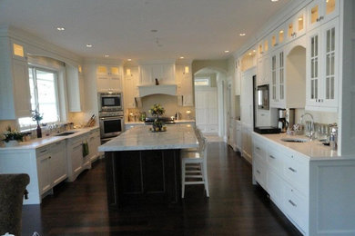 Inspiration for a mid-sized transitional l-shaped dark wood floor enclosed kitchen remodel in Vancouver with a drop-in sink, shaker cabinets, white cabinets, marble countertops, beige backsplash, stainless steel appliances and an island