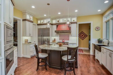 Inspiration for a large transitional l-shaped medium tone wood floor eat-in kitchen remodel in Chicago with a farmhouse sink, recessed-panel cabinets, white cabinets, granite countertops, white backsplash, subway tile backsplash, stainless steel appliances and an island