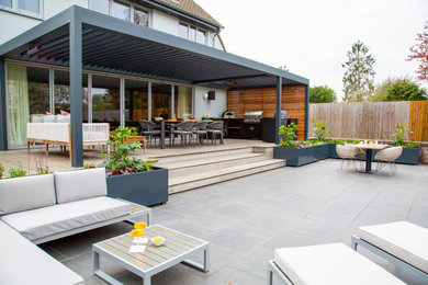 Design ideas for a medium sized contemporary back patio in Essex with an outdoor kitchen, decking and a pergola.