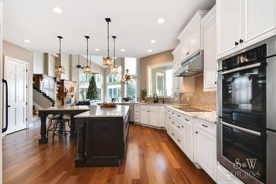 Example of a huge transitional l-shaped medium tone wood floor and brown floor open concept kitchen design in Orlando with an undermount sink, flat-panel cabinets, white cabinets, quartz countertops, beige backsplash, porcelain backsplash, paneled appliances and an island
