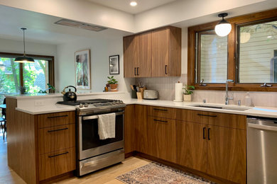 他の地域にある高級な小さなミッドセンチュリースタイルのおしゃれなキッチン (シングルシンク、フラットパネル扉のキャビネット、中間色木目調キャビネット、クオーツストーンカウンター、ピンクのキッチンパネル、セラミックタイルのキッチンパネル、シルバーの調理設備、淡色無垢フローリング、茶色い床、白いキッチンカウンター) の写真