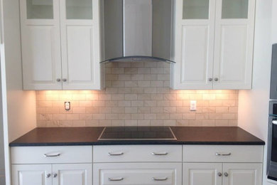 Eat-in kitchen - mid-sized traditional single-wall eat-in kitchen idea in Milwaukee with raised-panel cabinets, white cabinets, solid surface countertops, white backsplash, subway tile backsplash and stainless steel appliances