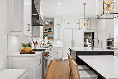 Inspiration for a large transitional u-shaped light wood floor kitchen remodel in Other with an undermount sink, shaker cabinets, white cabinets, quartz countertops, white backsplash, marble backsplash, paneled appliances, two islands and white countertops