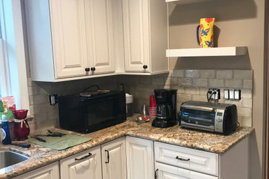 Enclosed kitchen - mid-sized contemporary l-shaped medium tone wood floor and brown floor enclosed kitchen idea in Los Angeles with an undermount sink, raised-panel cabinets, yellow cabinets, granite countertops, beige backsplash, subway tile backsplash, black appliances, an island and brown countertops