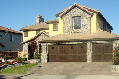 Large mediterranean yellow two-story stone exterior home idea in Los Angeles