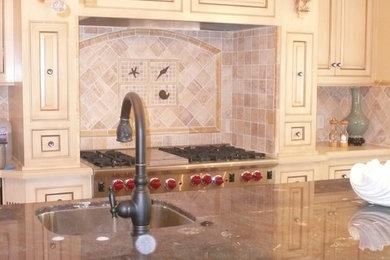 Enclosed kitchen - large traditional galley dark wood floor enclosed kitchen idea in Orange County with an undermount sink, beaded inset cabinets, white cabinets, beige backsplash, stone tile backsplash, stainless steel appliances and an island