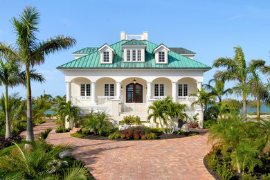 Example of a large island style beige two-story stucco house exterior design in Miami with a metal roof