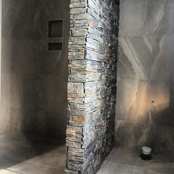 floor to ceiling tiles with a feature schist wall to seperate walk in shower fro