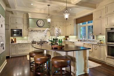 Example of a large transitional l-shaped dark wood floor and brown floor kitchen design in Seattle with a farmhouse sink, beaded inset cabinets, beige cabinets, quartzite countertops, paneled appliances and an island