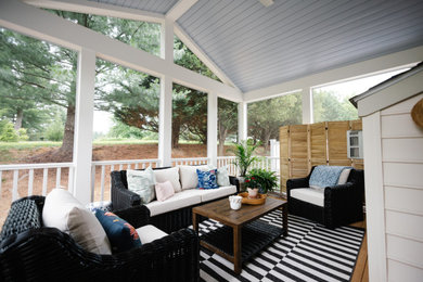 This is an example of a small traditional screened-in back porch design in Baltimore with a roof extension.