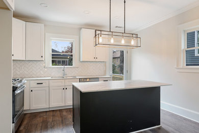 Arts and crafts medium tone wood floor and brown floor kitchen photo in Atlanta with an undermount sink, shaker cabinets, white cabinets, quartzite countertops, white backsplash, ceramic backsplash, stainless steel appliances, an island and multicolored countertops