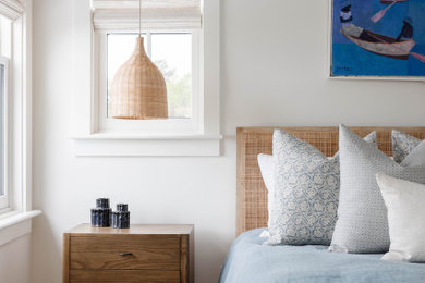 Example of a beach style medium tone wood floor and brown floor bedroom design with white walls