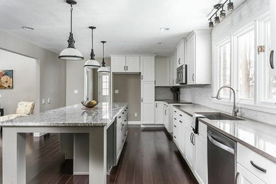 Inspiration for a transitional l-shaped dark wood floor and beige floor eat-in kitchen remodel with an undermount sink, shaker cabinets, white cabinets, granite countertops, white backsplash, matchstick tile backsplash, stainless steel appliances and an island