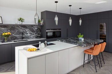 Photo of a large contemporary l-shaped eat-in kitchen in London with flat-panel cabinets, black cabinets and with island.