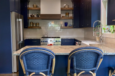 Example of a classic kitchen design in Detroit with a farmhouse sink, blue cabinets, white backsplash, ceramic backsplash and stainless steel appliances