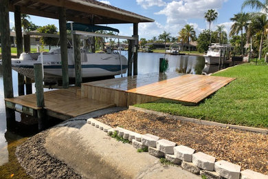 Example of a mid-sized island style backyard dock design in Miami with no cover