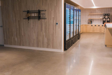 Example of a large trendy u-shaped concrete floor and gray floor open concept kitchen design in San Francisco with flat-panel cabinets, light wood cabinets, quartz countertops, white backsplash, ceramic backsplash, stainless steel appliances, an island and white countertops