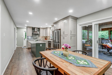 Eat-in kitchen - l-shaped medium tone wood floor and brown floor eat-in kitchen idea in DC Metro with an undermount sink, shaker cabinets, green cabinets, quartz countertops, green backsplash, subway tile backsplash, stainless steel appliances, an island and white countertops